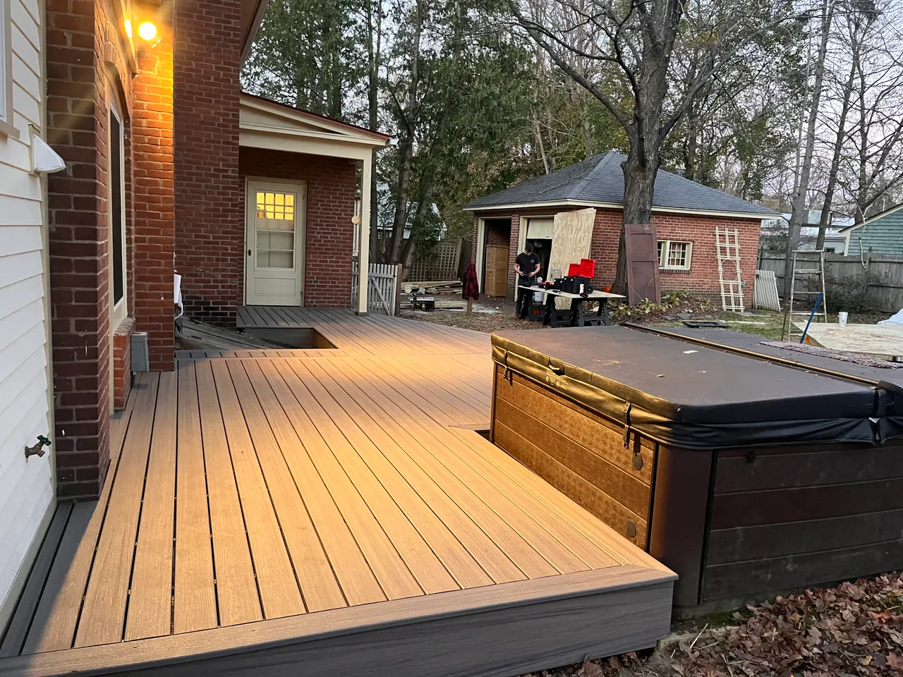 Finished composite deck along a brick house with a hot tub