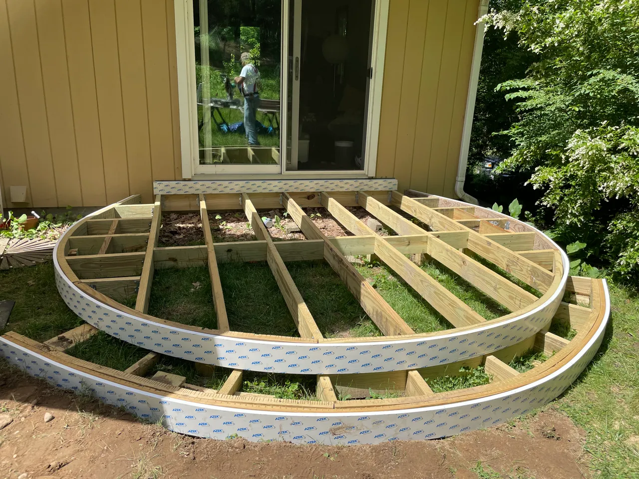 Curved deck framing with bent rim joists outside a sliding door