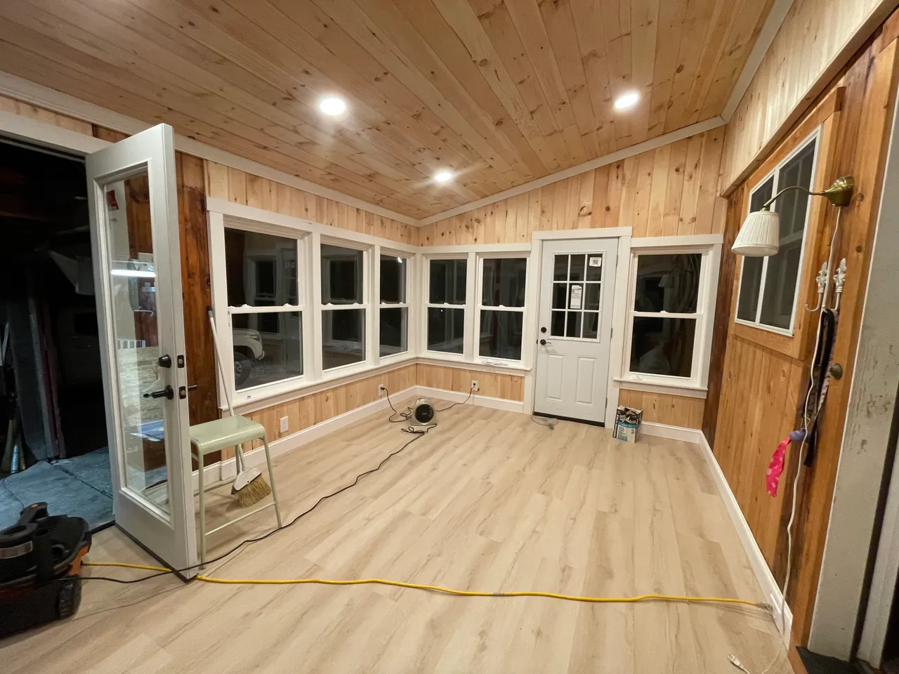 Renovated porch with new windows, pine ceiling, recessed lights and light floor