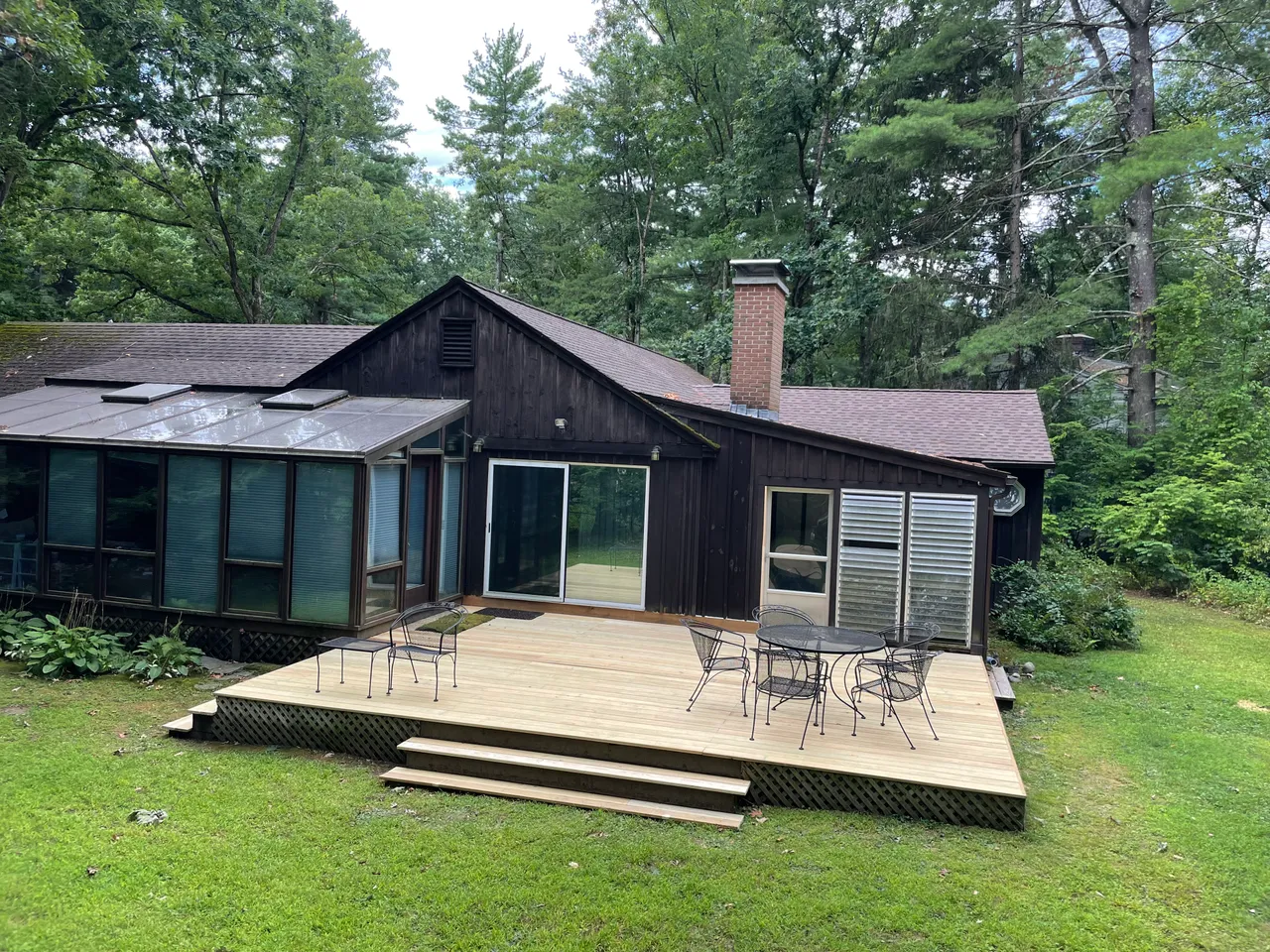 Large new wood deck with stairs behind a dark-sided house