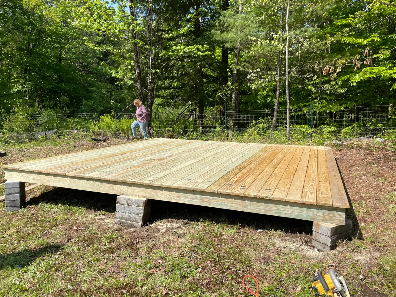 Pressure-treated platform deck on blocks in a wooded yard