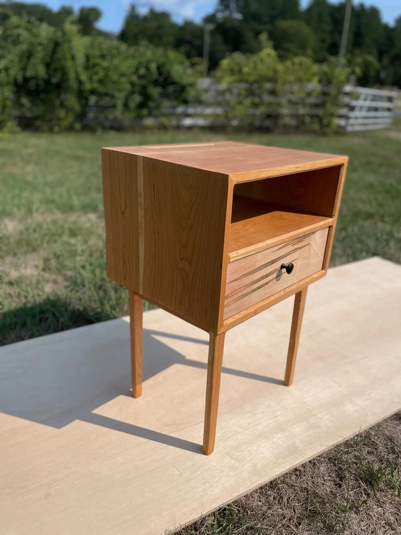 Hardwood nightstand with a drawer and open shelf, outdoors