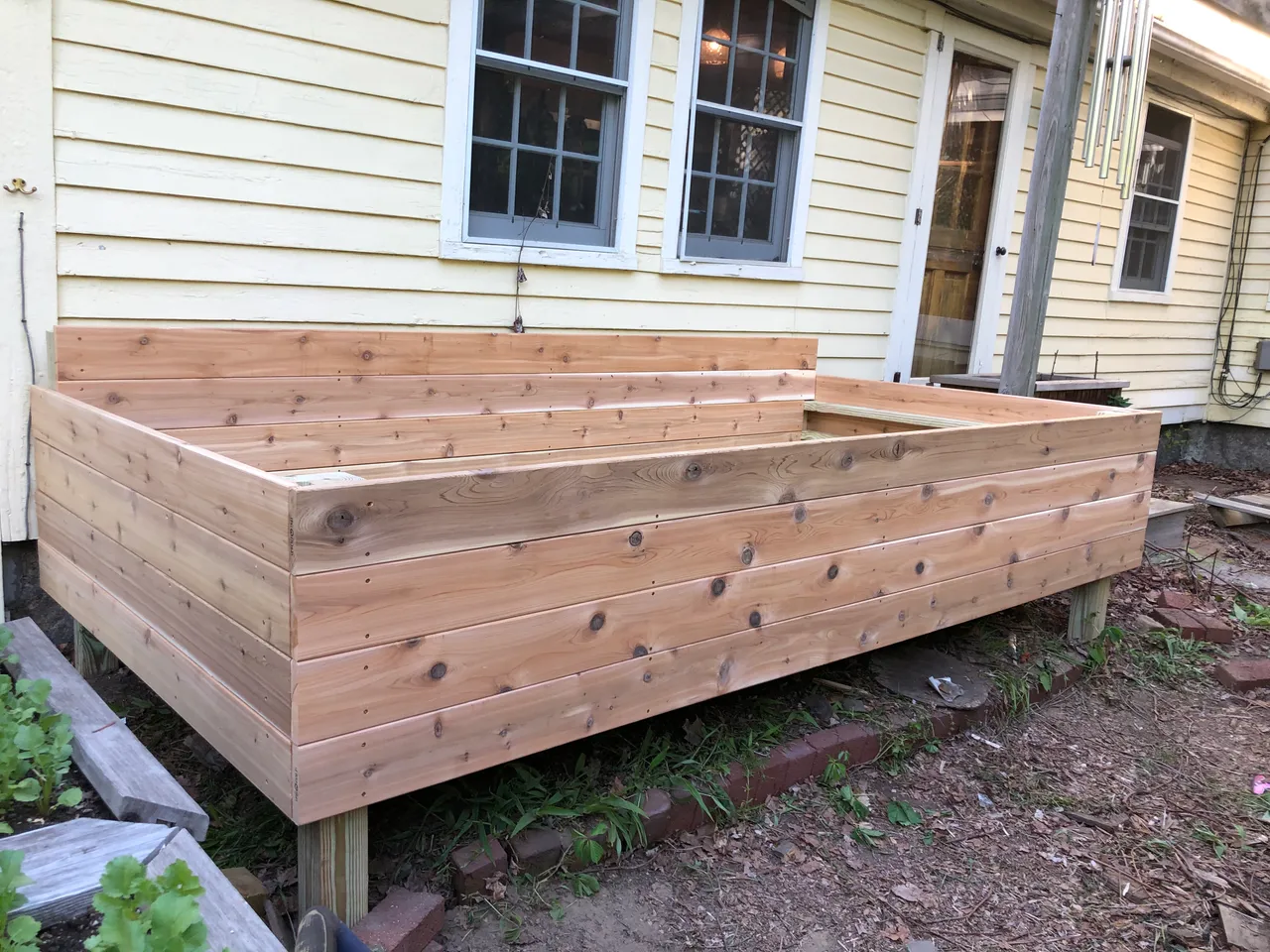 Wooden raised garden bed beside a house