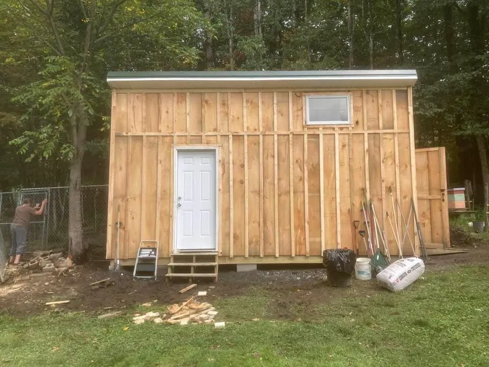 New board-and-batten shed with a window and white door
