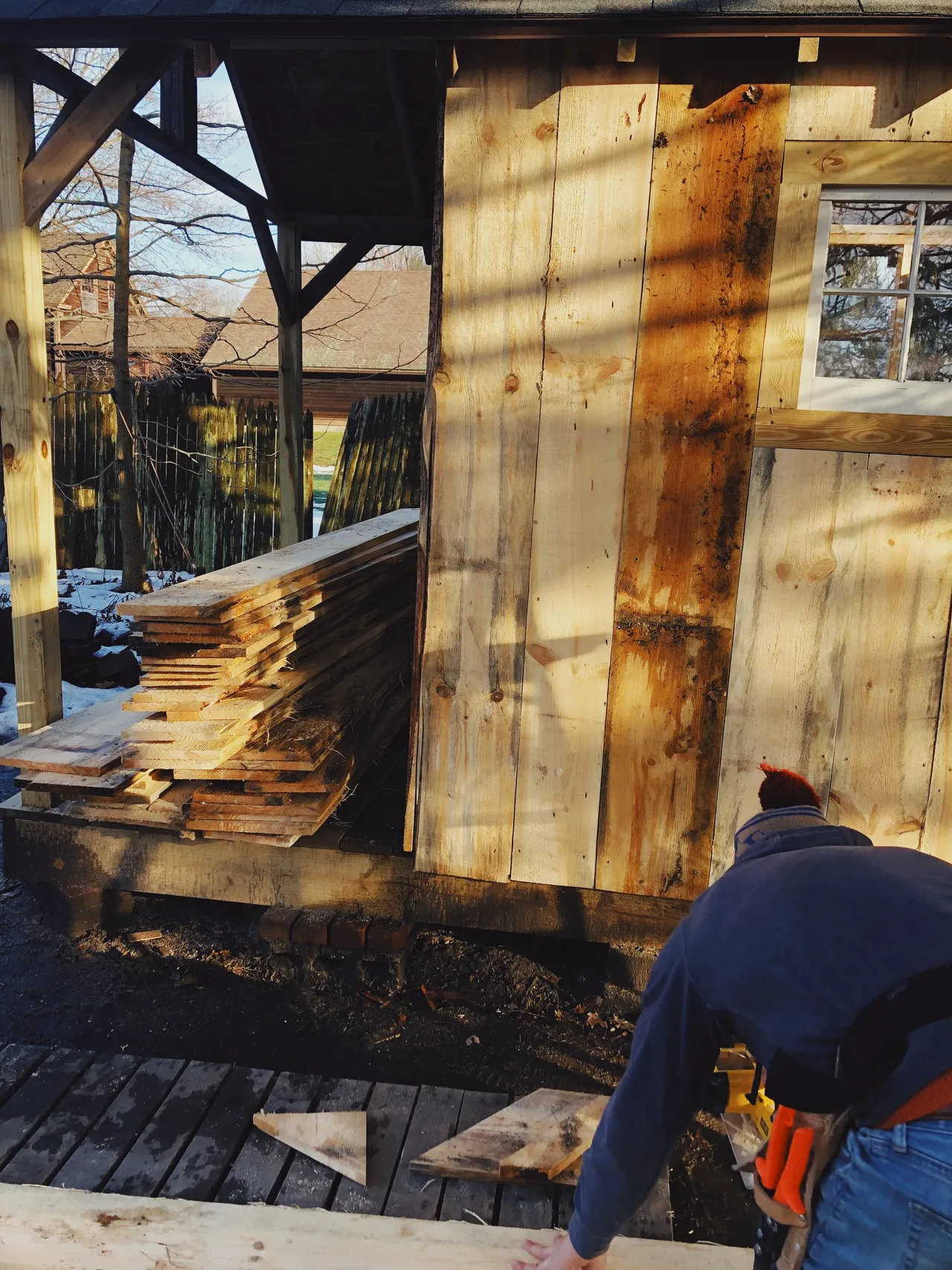 Reclaimed boards being installed as cabin siding