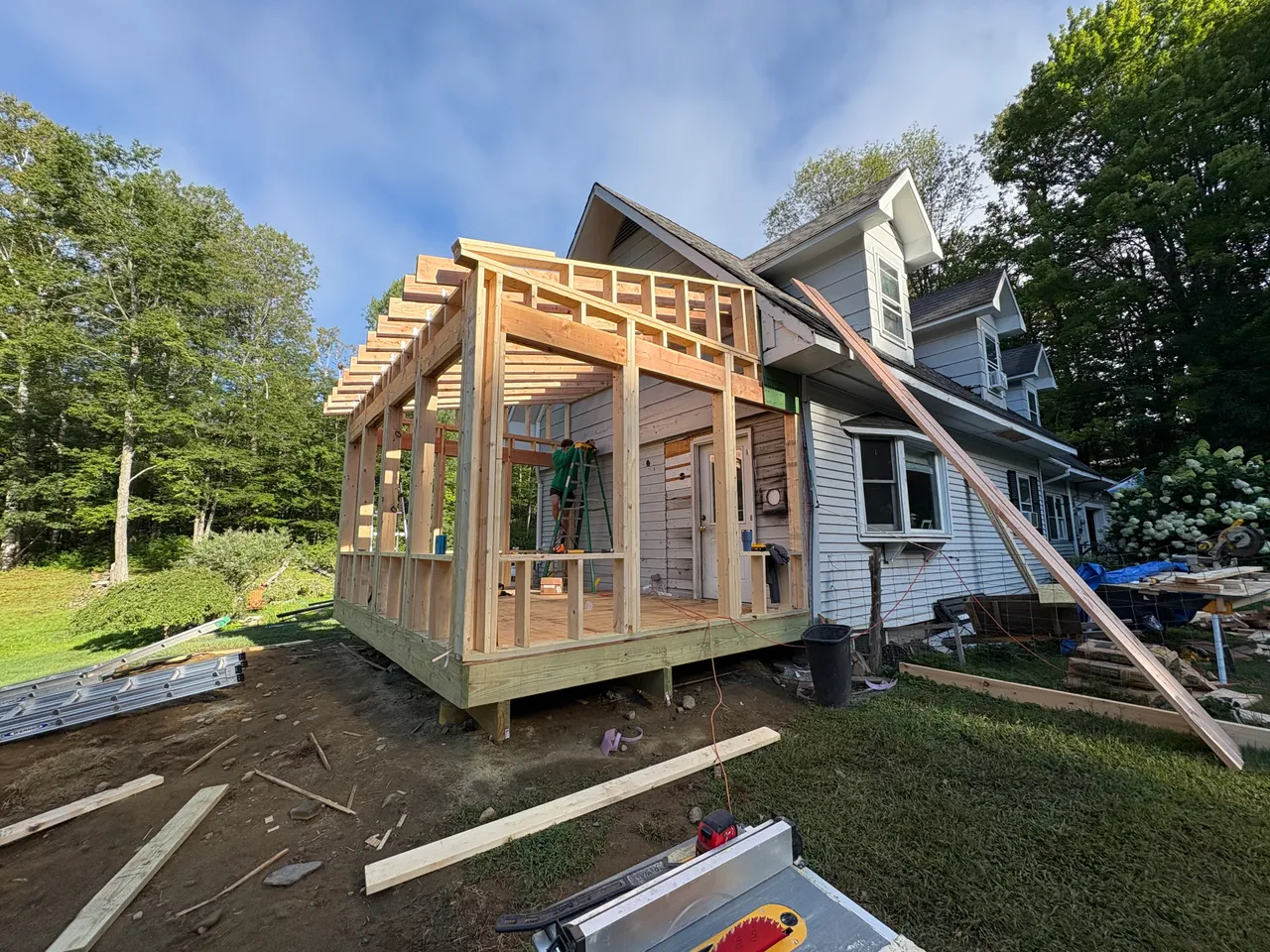Sunroom walls and roof framed against the side of the farmhouse